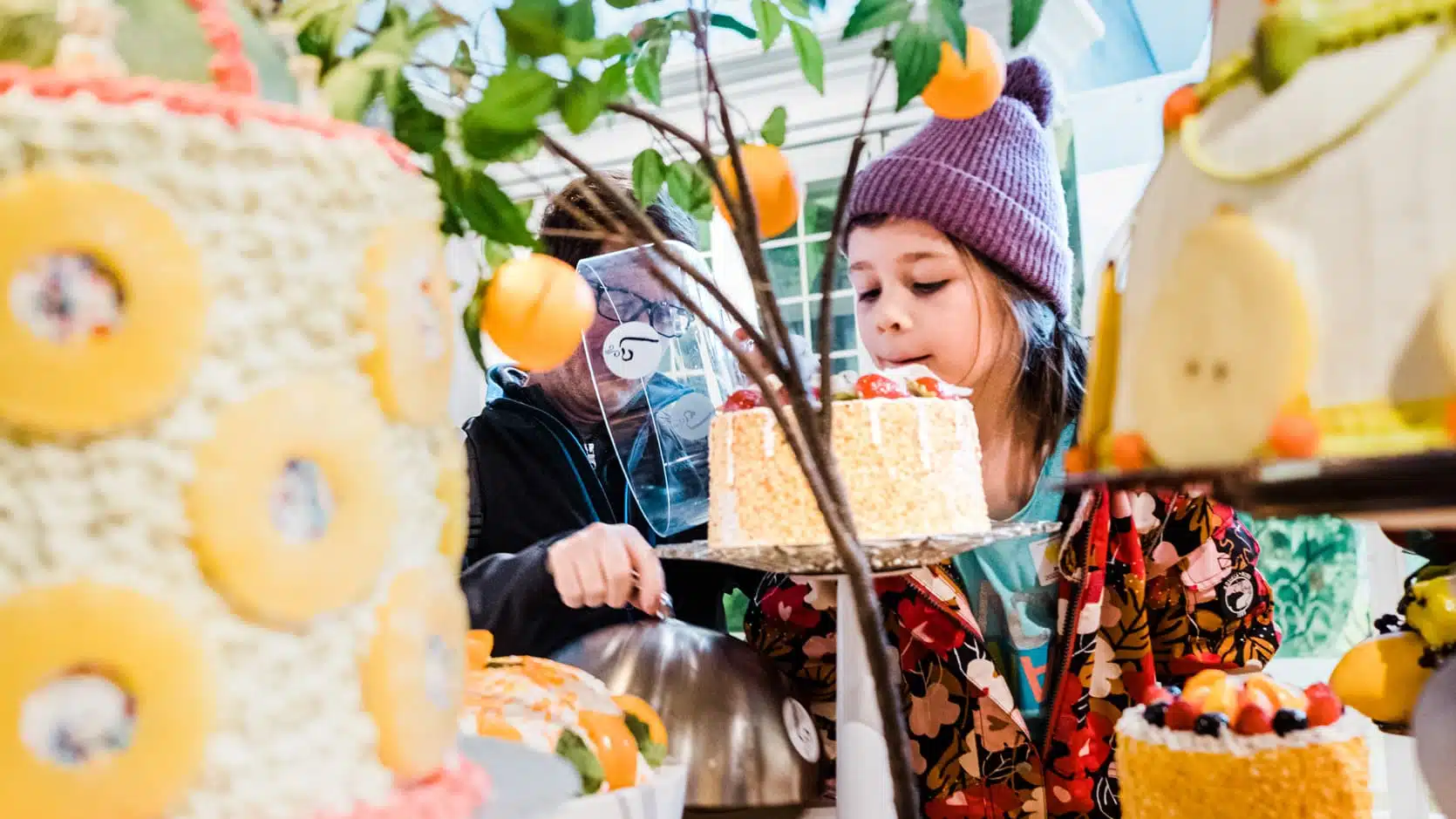Jeune fille sentant un gâteau la table de fausse nourriture de l'exposition jeunesse Ma maison