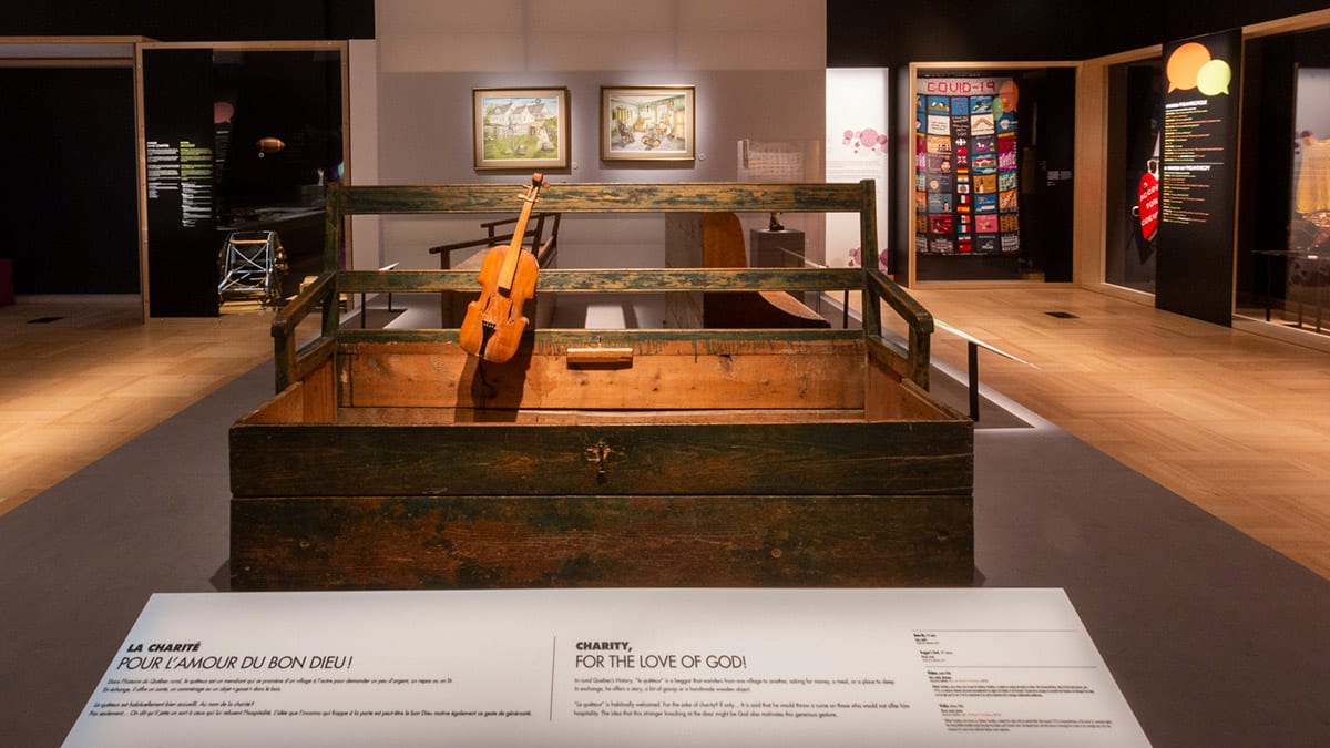 Un banc de quêteux et un violon fait à la main mis en valeur dans l'exposition Générosité.