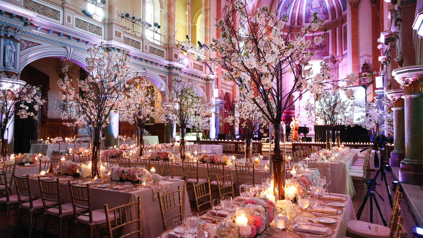 Chapelle du Séminaire de Québec en formule mariage avec des tables longues nappées en blanc, des chaises dorées et des arrangements floraux très grands.