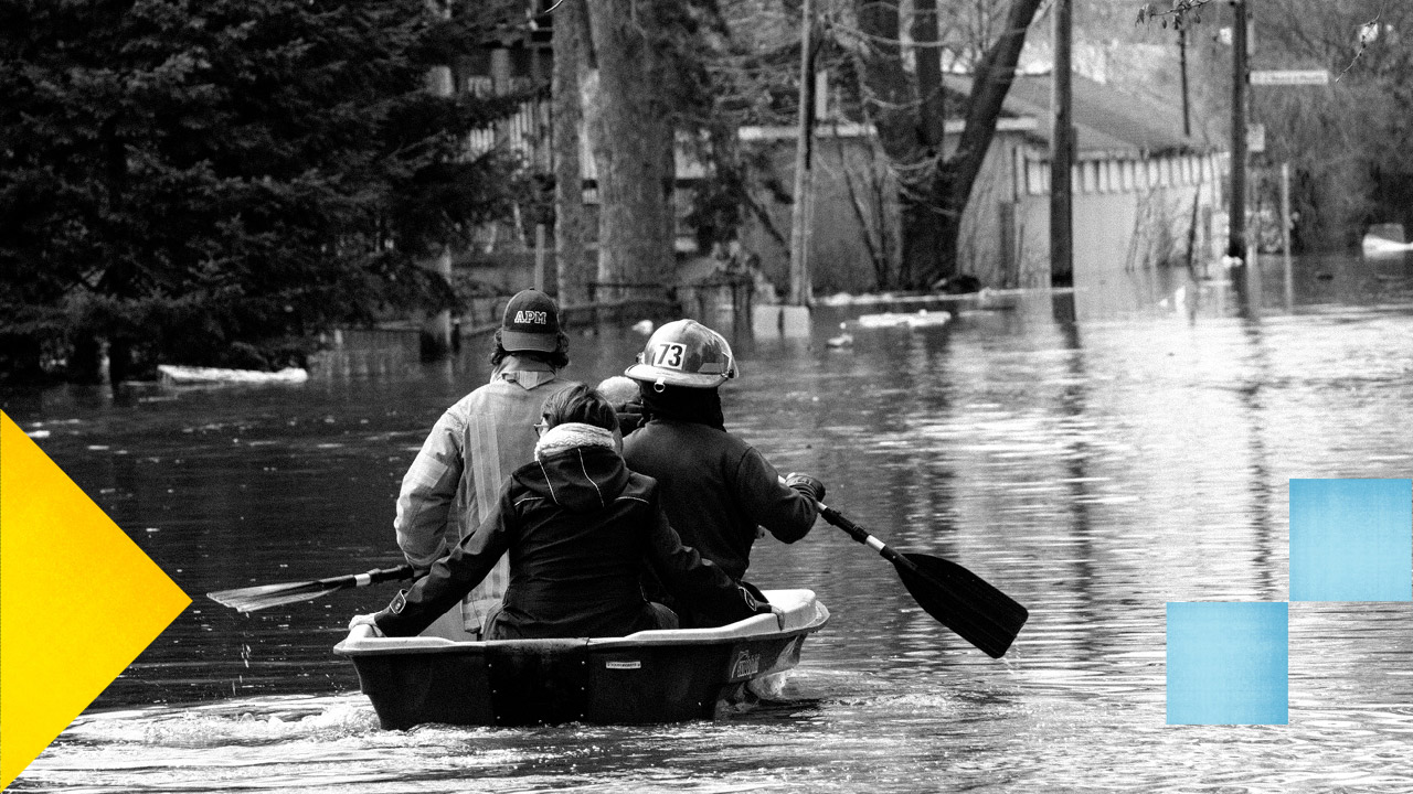 Photo en noir et blanc d'un pompier et de deux personnes dans une chaloupe sur l'eau lors d'inondation.