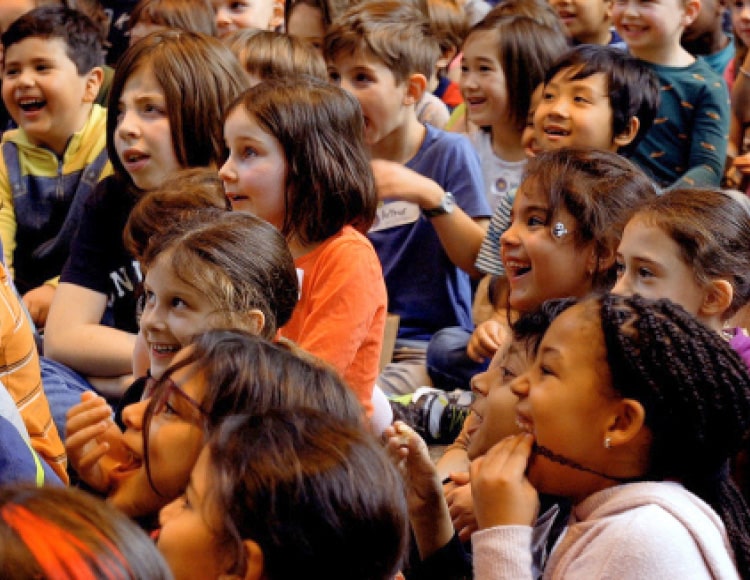 Plusieurs enfants assis dans le Hall du Musée lors d'un spectacle offert dans le cadre de Tout un monde