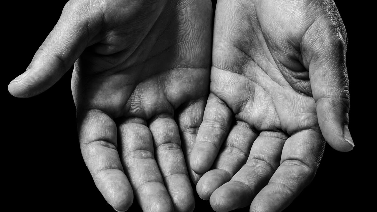 Image en noir et blanc de mains recueillies en symbole d'aumône.