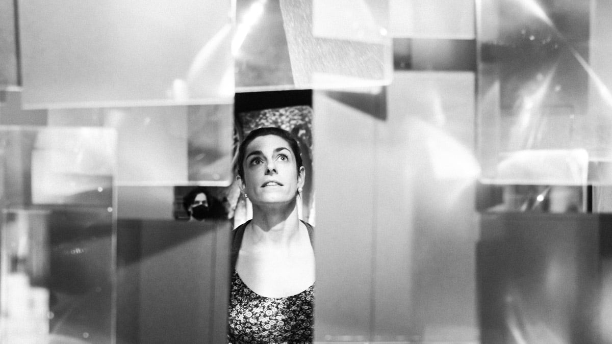 Photographe en noir et blanc d'une visiteuse admirant une oeuvre accrochée au plafond.