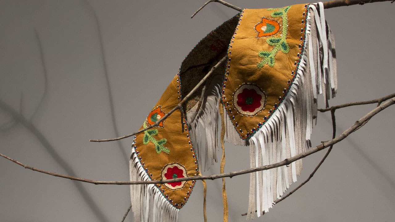 Col autochtone féminin en cuir perlé avec frange suspendu à un arbre.