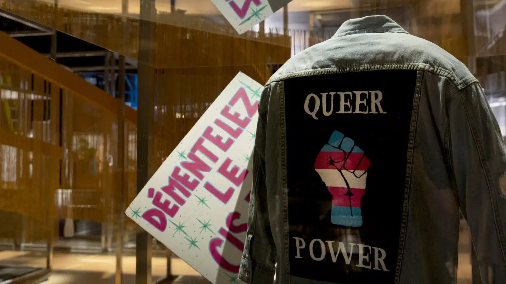Vue d'une veste de dos sur laquelle on peut lire Queer Power avec un point de manifestation.