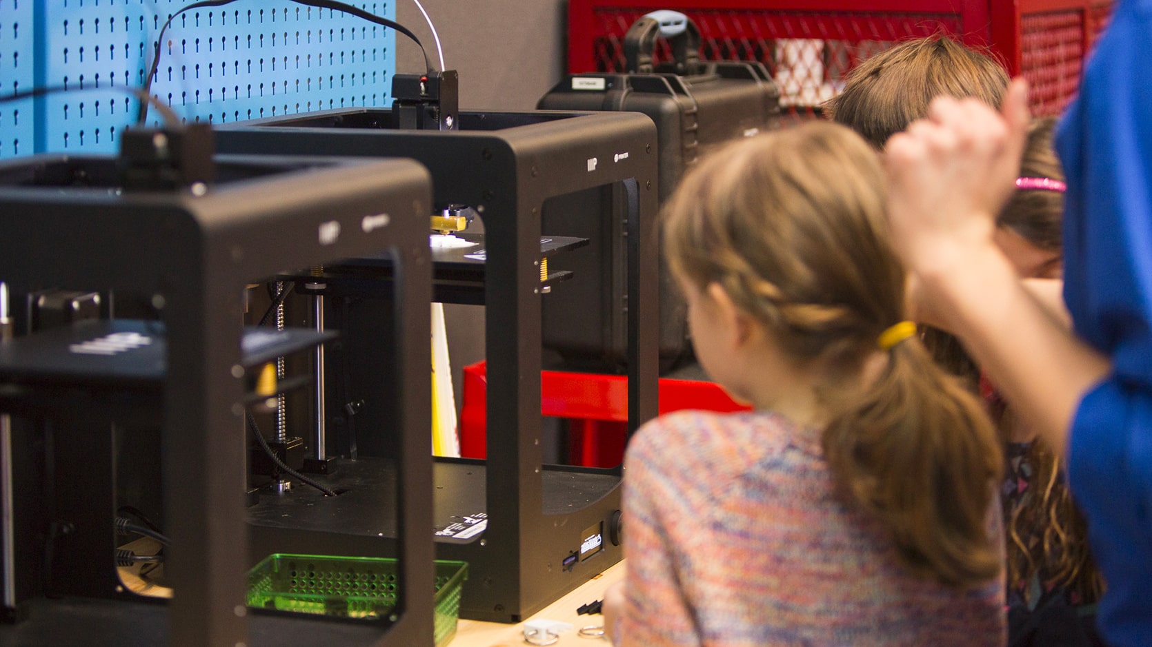Deux enfants admirent une imprimante 3D en action.