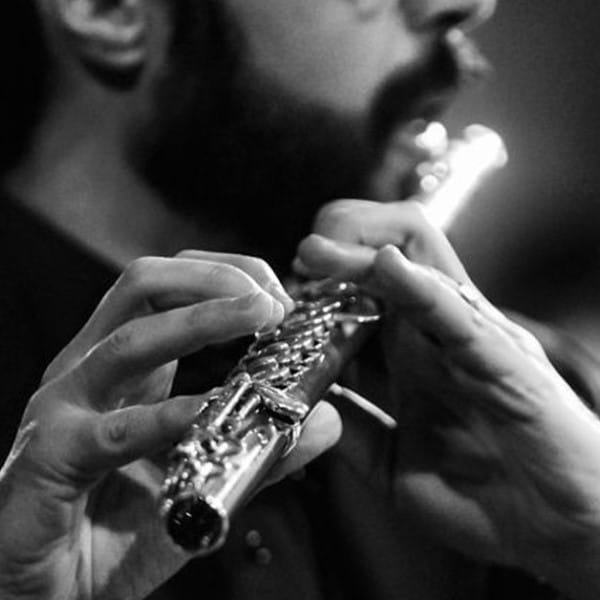 Image en noir et blanc d'un homme barbu qui joue de la flûte traversière