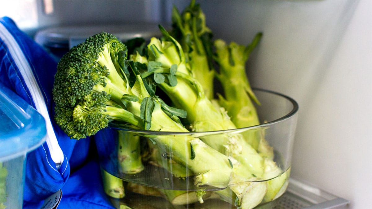Pied de brocoli conservé dans une bol d'eau dans un frigo.