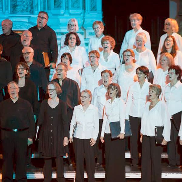 Choristes vêtus de blanc et de noir chantant devant le choeur de la Chapelle du Séminaire