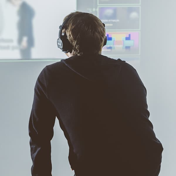 Photo d'un personne placée de dos, face à une projection et portant un casque d'écoute