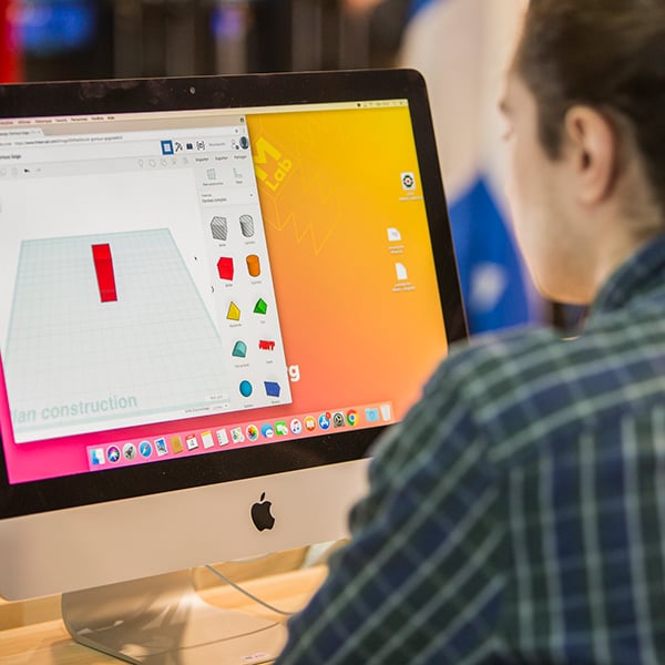Une personne de dos devant un iMac qui test un logiciel de modelisation 3D au MLab Creaform