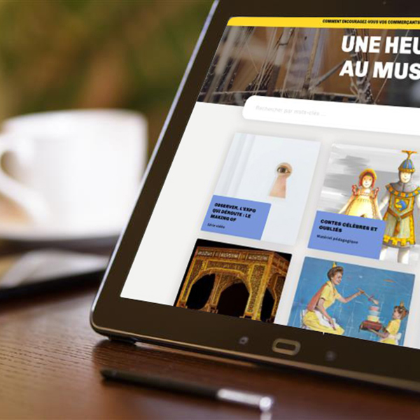 Un iPad présenté le site Une heure au Musée devant une tasse de café