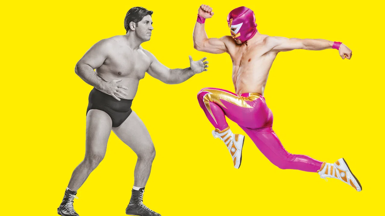 Deux lutteurs en mouvement sont face à face. Celui de gauche est en noir et blanc, celui de droite porte un masque et un pantalon fushia et doré.