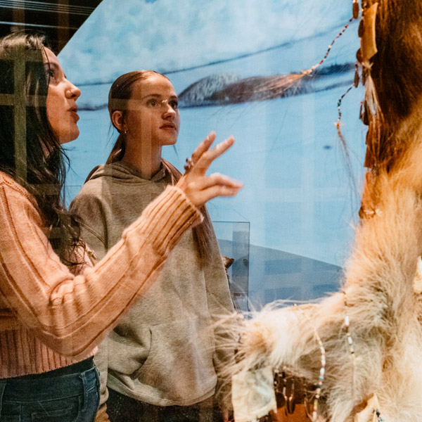 deux filles adolescentes aux cheveux longs observent une oeuvre autochtones