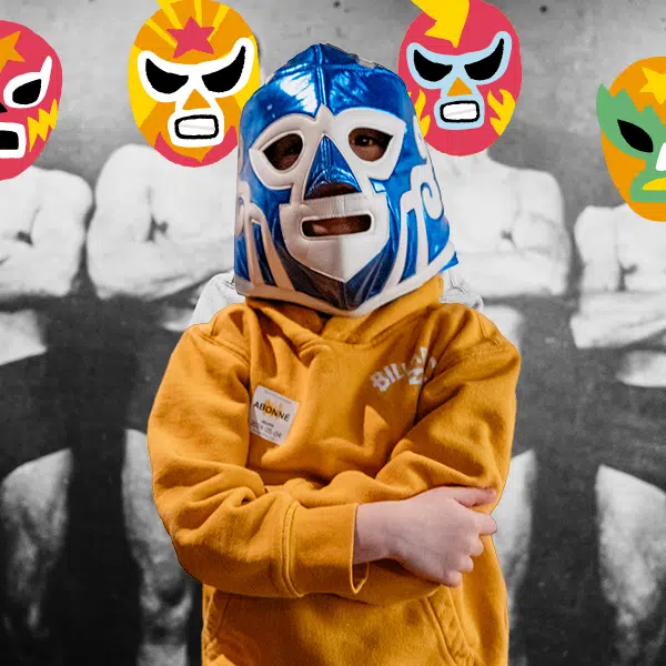 image d'un enfant avec un gilet kangourou jaune moutarde qui porte un masque de lutteur mexicain avec en arrière-plan une photo noir et blanc d'anciens lutteurs sur laquelle a été apposé un masque de lutteur mexicain à la place de leur tête