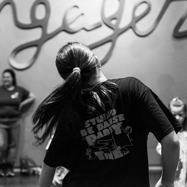 photo noir et blanc d'une danseuse de rap prise de dos portant un t-shirt du Studio de danse Party Time et une queue de cheval