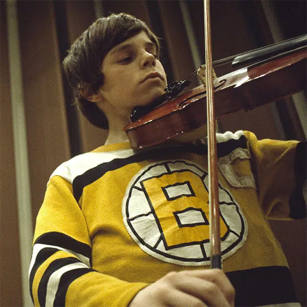 photo d'un garçon jouant du violon vêtu d'un chandail de hockey de l'équipe des Bruins de Boston de couleur noir et jaun