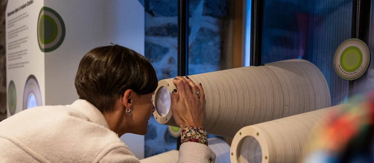 Femme en train de regarder à l'intérieur d'un module d'interprétation ayant une forme conique.