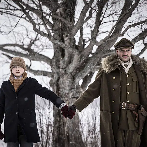 image tirée du film Le cube de sucre où l'on voit un garçon avec une tuque et un manteau noir mi-long tenir la main d'un soldat en uniforme et manteau kaki devant un arbre en hiver