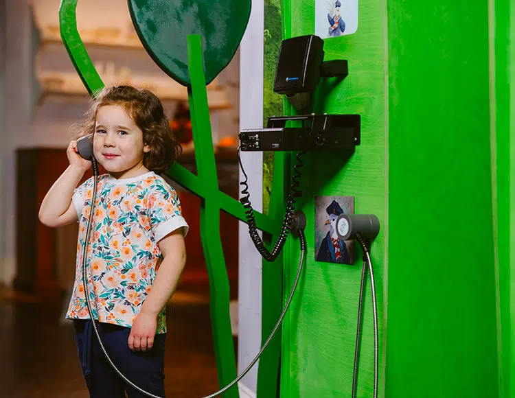 Une petite fille tient un téléphone dans une exposition.