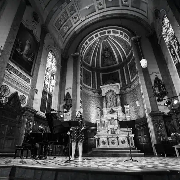 photo noir et blanc d'une chanteuse lyrique sur la scène de la Chapelle accompagné d'une pianiste