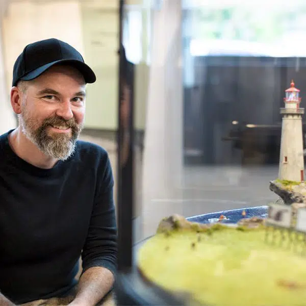 Photographie de l'artiste Vano Hotton en buste à côté de son oeuvre le Trompe oreille.