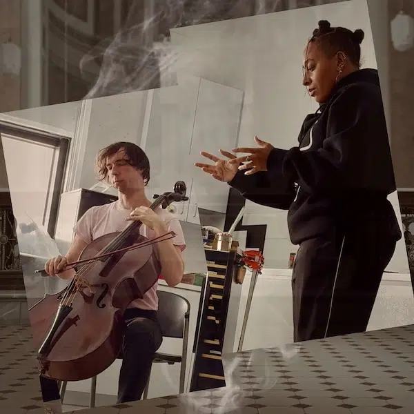 photo des deux artistes en répétition dans un local : un violoniste assis sur une chaise et une femme noire debout à ses côtés de profil avec les bras tendus vers l'avant