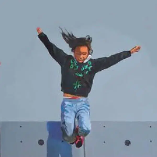 image d'un jeune adulte sautant d'un mur les bras levés vers le ciel et les jambes repliés