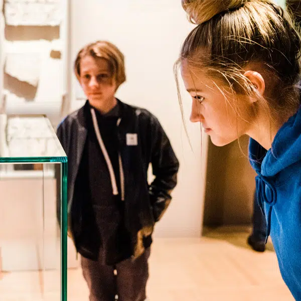 Deux adolescents qui regardent un objet placé dans une vitrine 