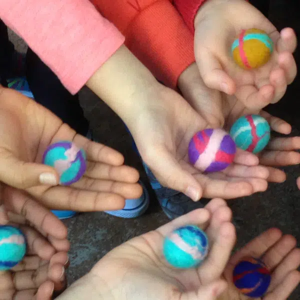 photo où on voit des mains tenir des boules de laine feutrée