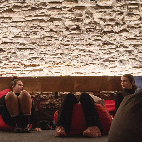 trois personnes sont assis sur des poufs près du sol dans une cave voûtée